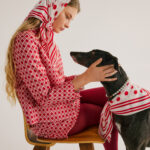 Young woman and greyhound in matching scarves gaze into each others eyes